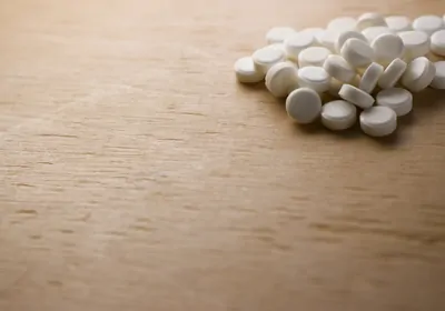 Round white pills on a wooden surface Round white pills on a wooden surface